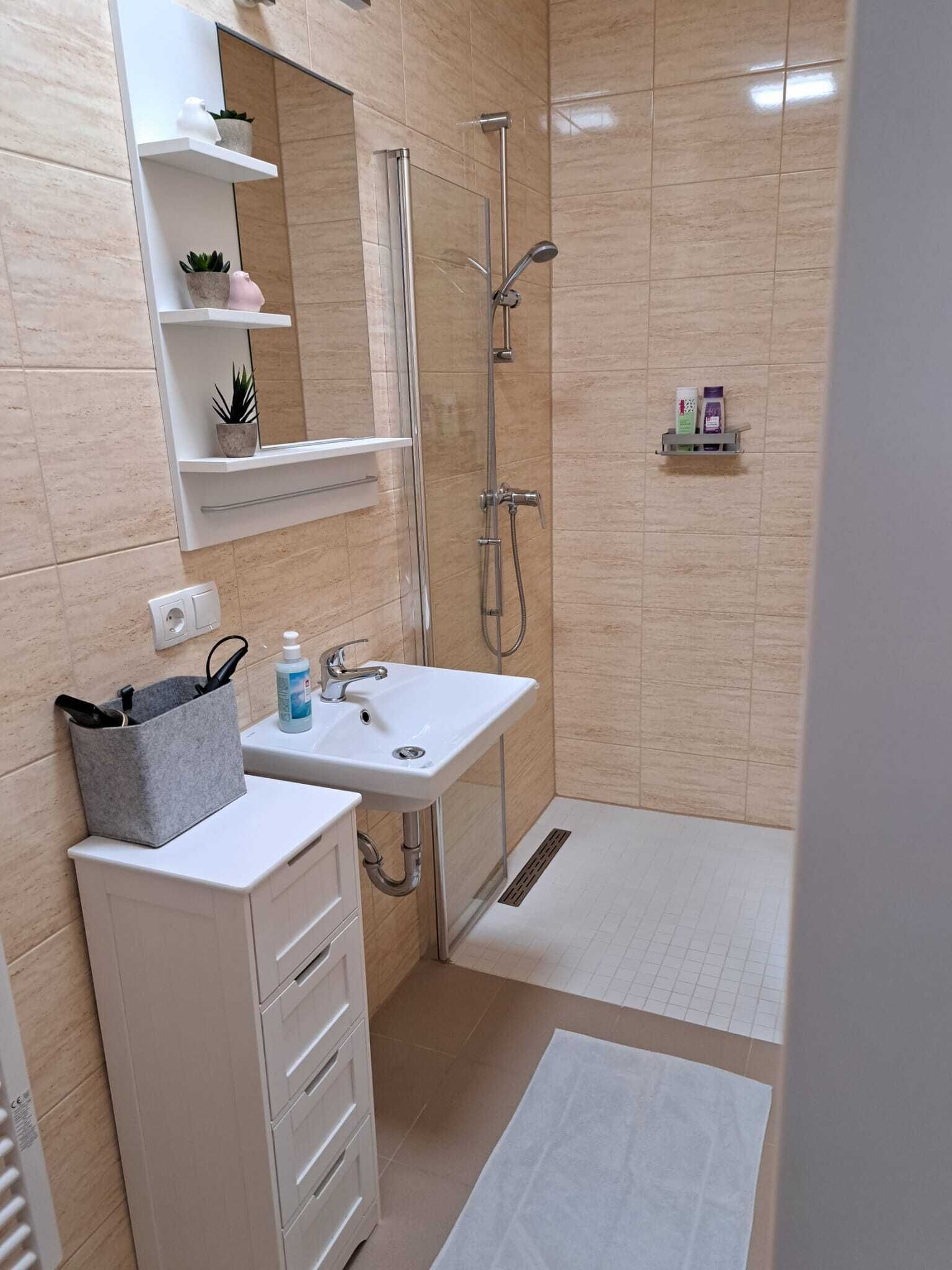 A modern bathroom with a shower, sink, and storage cabinets.
