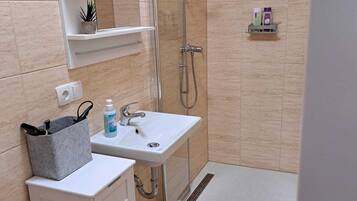 A modern bathroom with a shower, sink, and storage cabinets.