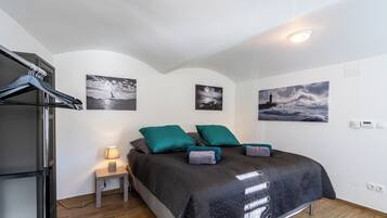 A bedroom with a bed, a nightstand, a lamp, and three wall-mounted paintings.
