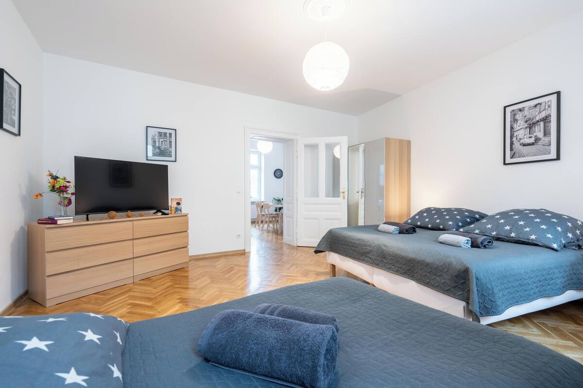Ein Schlafzimmer mit einem Bett, einem Fernseher, einer Kommode und einer Tür zu einem anderen Raum.