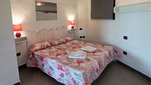 A bedroom with a bed, two bedside tables, a wall-mounted TV, and a red lamp. - Relaxation and comfort come together in an oasis of peace. Authentic Sardinia is waiting for you! (Porto Istana)