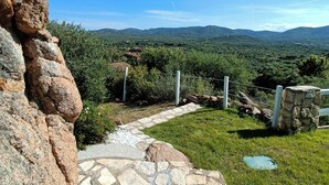 A stone pathway leading to a stone wall with a metal showerhead. - Relaxation and comfort come together in an oasis of peace. Authentic Sardinia is waiting for you! (Porto Istana)