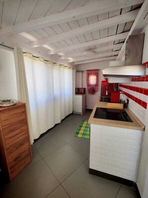 Une cuisine avec un mur recouvert de carreaux blancs, un meuble en bois et un appareil électroménager rouge.