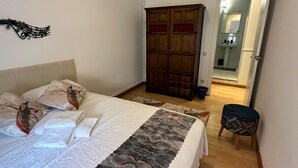 Un dormitorio con cama, almohadas, un armario y un baño visible a través de una puerta abierta.