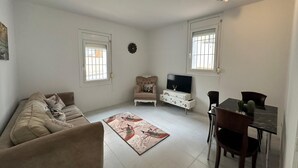 Una sala de estar con un sofá, un televisor, una mesa de comedor con sillas y una alfombra decorativa.