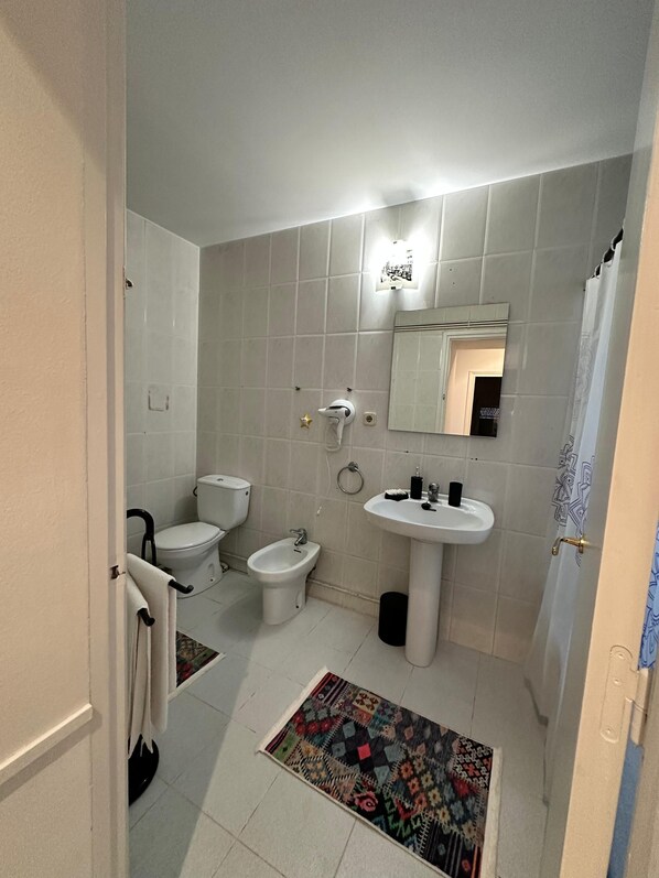 Un baño con inodoro, bidé, lavabo y espejo.
