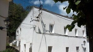 Un edificio blanco con un balcón y un coche rojo estacionado en la parte delantera.