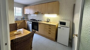 Una cocina compacta con armarios de madera, estufa a gas, microondas y lavavajillas.