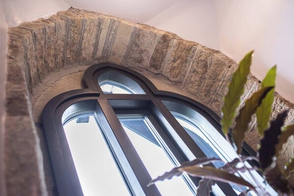 A stone archway with a window and a plant in the foreground.