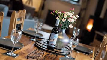 Une table à manger dressée avec des verres à vin, une bouteille de sherry et un vase rempli de fleurs.