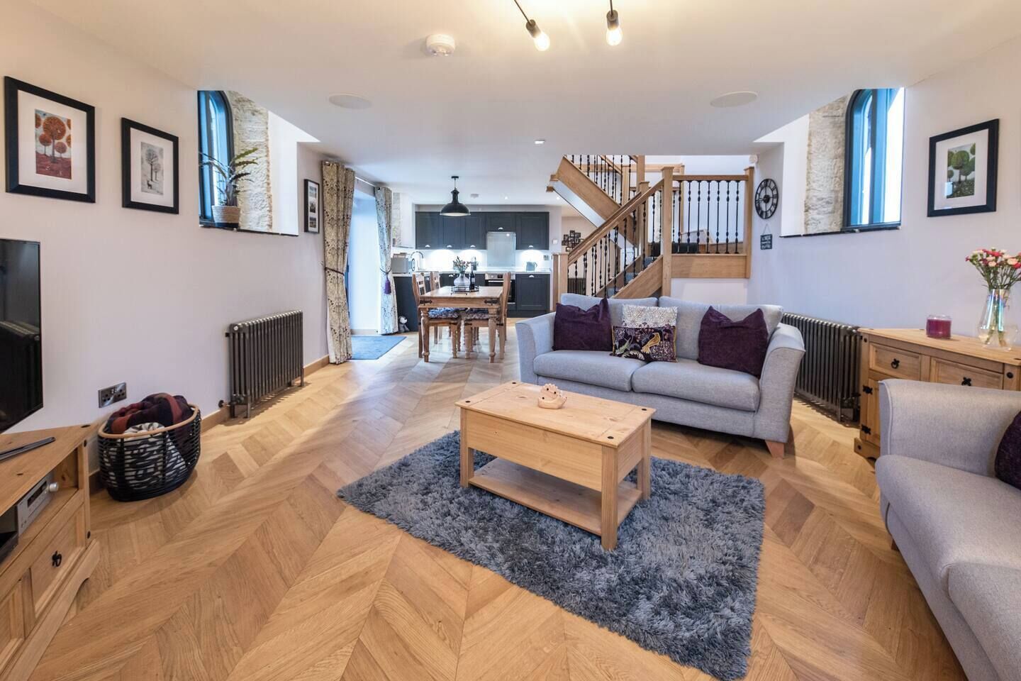 Een moderne woonkamer met een bank, salontafel en een trap die naar een keuken leidt.