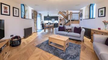 Een moderne woonkamer met een bank, salontafel en een trap die naar een keuken leidt.