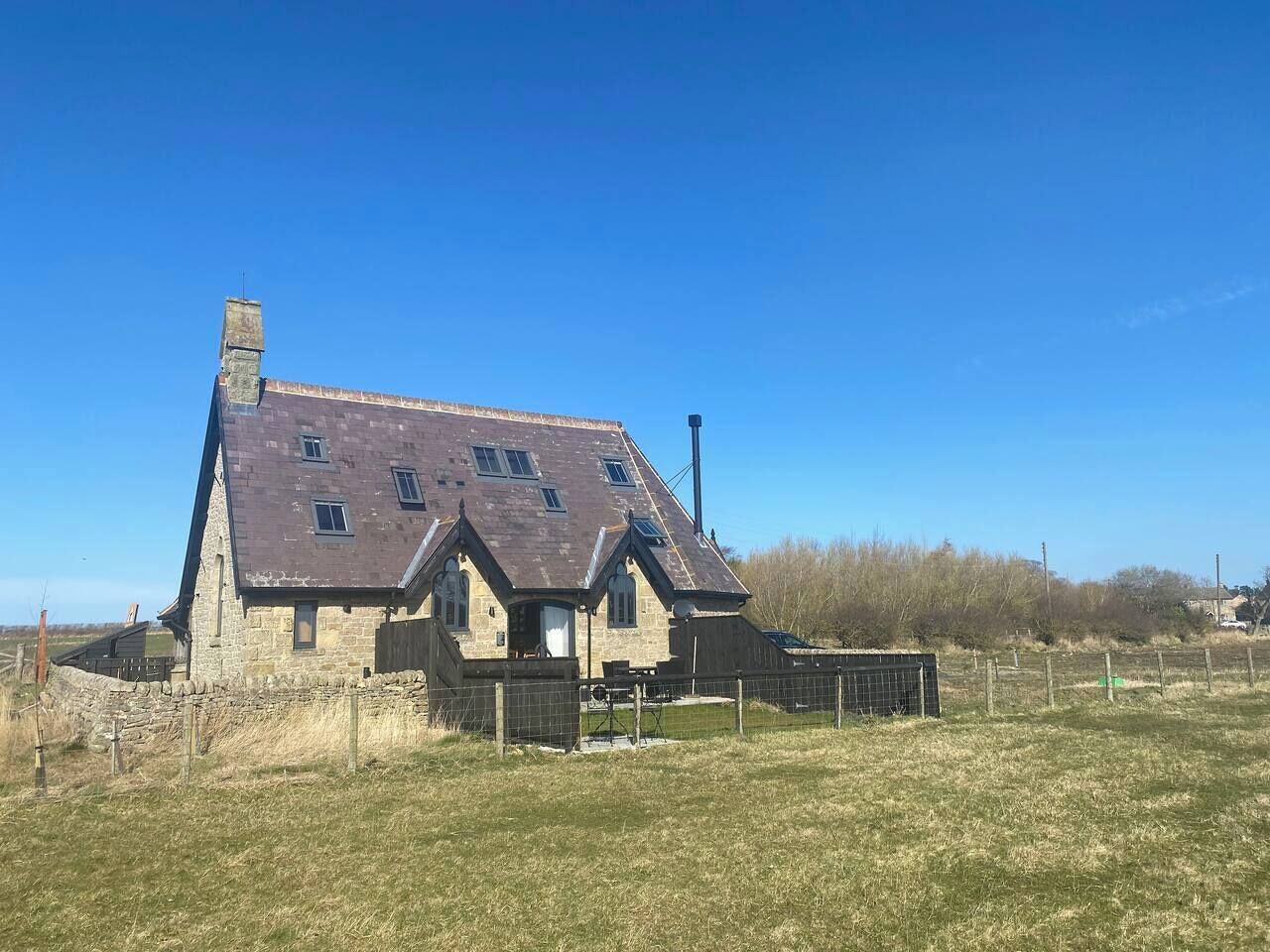 Une grande maison en pierre à deux étages, dotée d’un toit en pente et de nombreuses fenêtres.