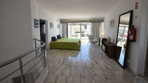 Une chambre d’hôtel équipée d’un lit, d’une chaise, d’un bureau, d’un extincteur et d’un balcon avec vue.