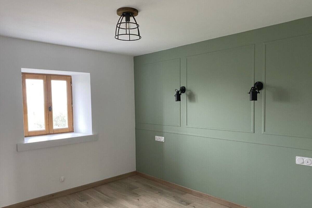 A room with a window, light switch, and a wooden floor.