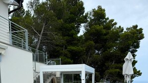 A swimming pool with lounge chairs and a covered seating area, surrounded by trees and overlooking a body of water. - Orizzonti Blu Pool Villa by Wonderful Italy (Cervo)