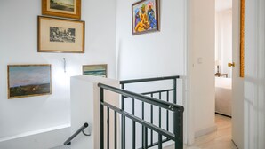 Una escalera con barandilla negra que lleva a un dormitorio.