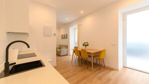 A modern kitchen with a sink, a dining area with a table and chairs, and a living room with a sofa.