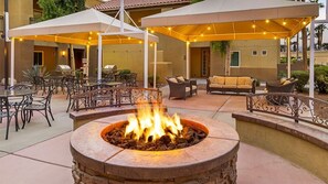 Une terrasse extérieure dotée d’un foyer, de coins salon et de parasols pour créer de l’ombre.