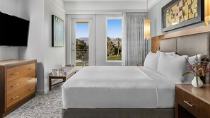 Une chambre d’hôtel avec un grand lit, une télévision, un bureau et une vue sur l’extérieur par les fenêtres.