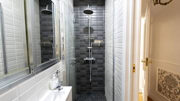 Un baño estrecho con ducha, lavabo y espejo.