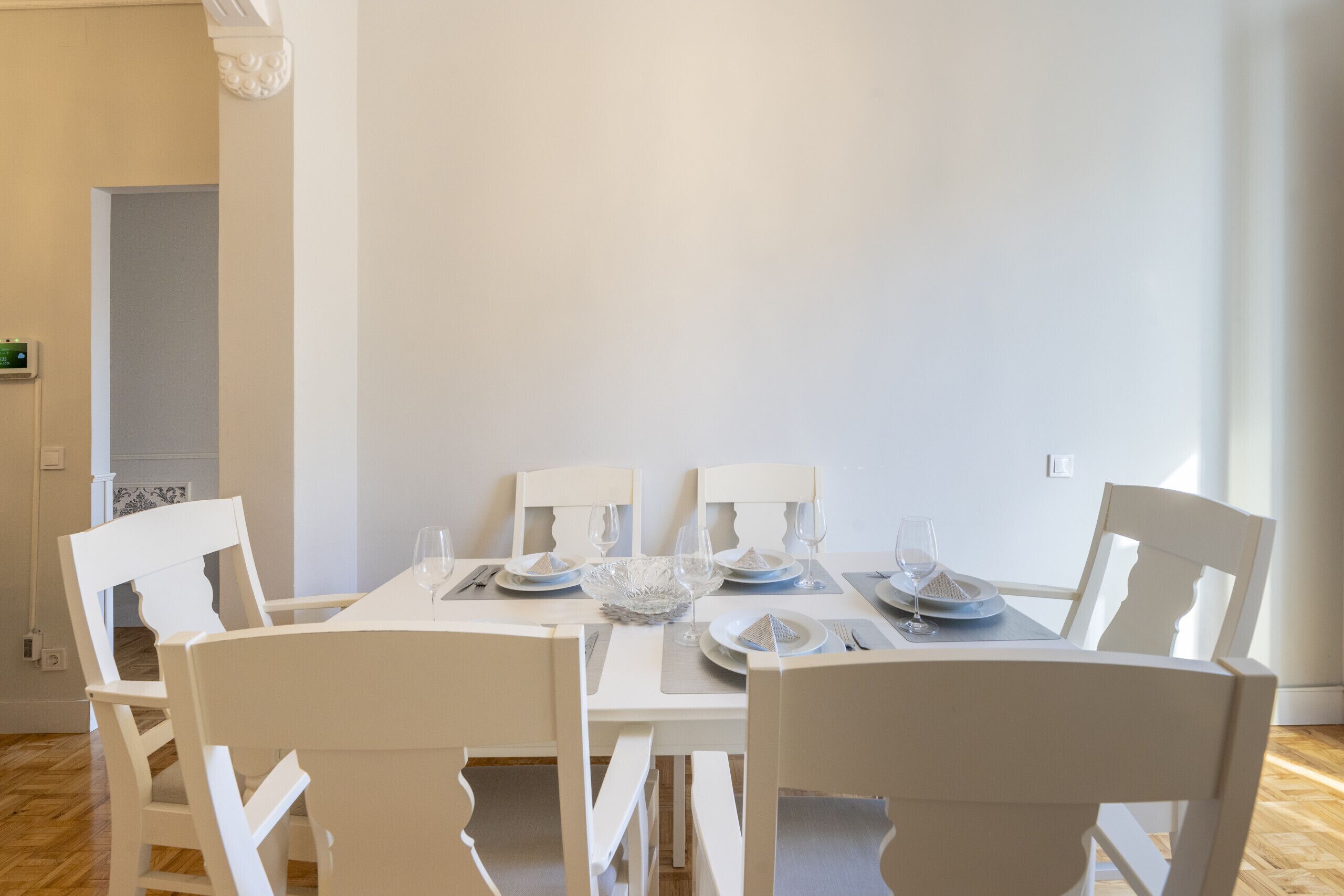 A dining area with a white table set for four, including plates, glasses, and cutlery.