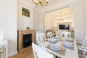 A dining room with a fireplace, white furniture, and a chandelier. - Cosy flat with balconies in the centre of Madrid, a few steps from the Plaza Mayor. (Madrid)