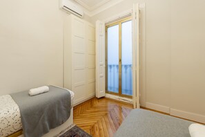 A room with two beds, a sliding glass door to a balcony, and a white wardrobe. - Cosy flat with balconies in the centre of Madrid, a few steps from the Plaza Mayor. (Madrid)