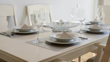 A dining table set with white plates, clear glasses, and a decorative glass bowl.