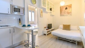 Una habitación compacta y moderna con kitchenette, comedor y cama.
