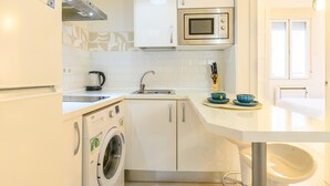 Cocina funcional con lavadora, microondas y lavaplatos.