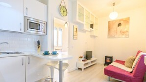 Una cocina moderna con armarios blancos, un microondas y una zona de comedor con taburetes.