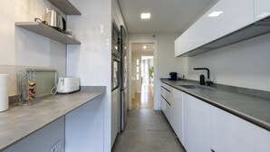 A modern kitchen with white cabinets, stainless steel appliances, and a grey countertop.