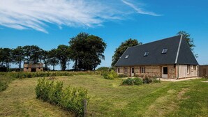 A large stone house with a sloped roof and a small attached barn.