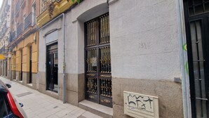 A building with a large window featuring a metal gate, a door, and a small signboard with a drawing.