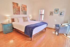 A bedroom with a bed, bedside tables, a chair, and artwork on the walls.