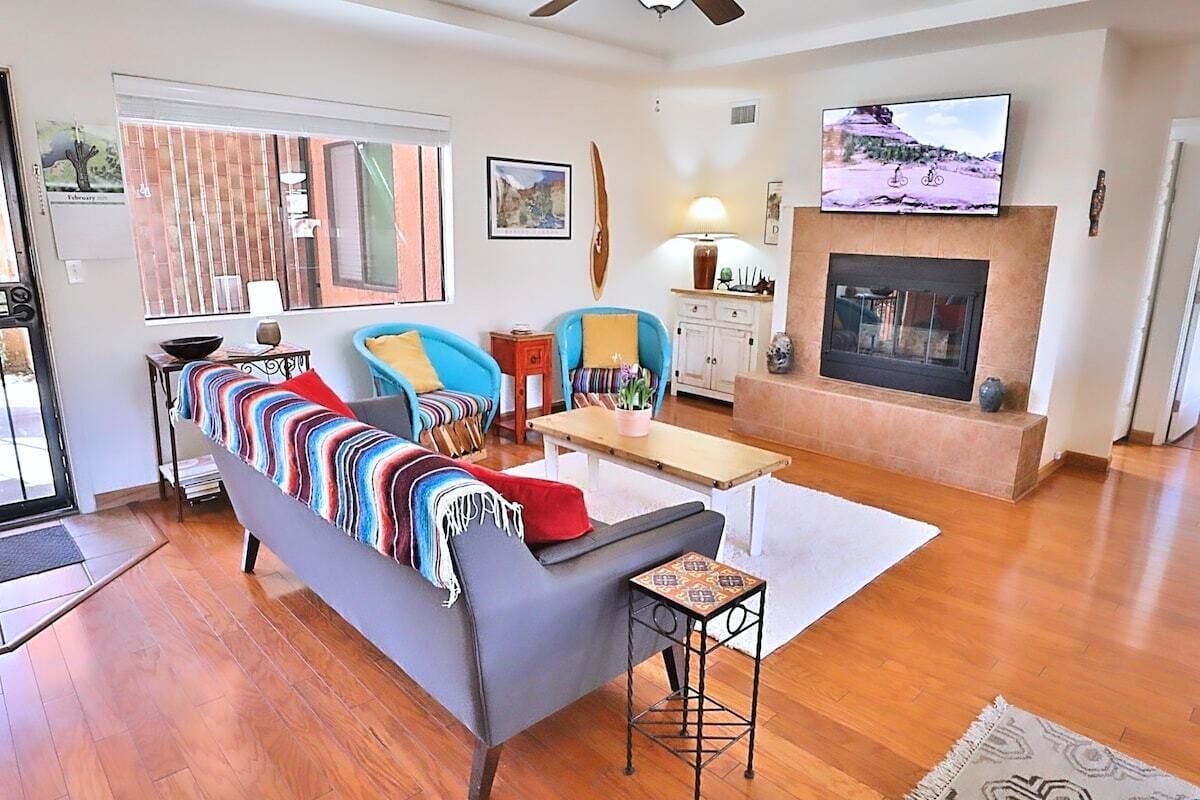 A living room with a sofa, armchairs, a coffee table, a fireplace, and a television mounted above it.