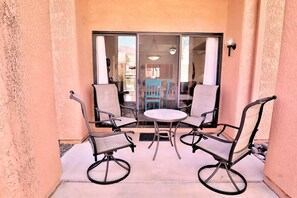 A patio with a table and four chairs, a sliding glass door, and a view of the interior.