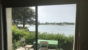 Una stanza con vista su un lago, un tavolo verde e due sedie.