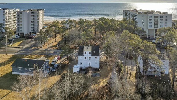 Una zona residencial costera con varios edificios de apartamentos, un estacionamiento y una playa al fondo.