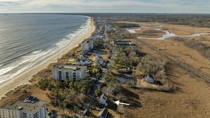 Vista aérea de una zona residencial costera con propiedades frente a la playa, una avenida principal y un río.