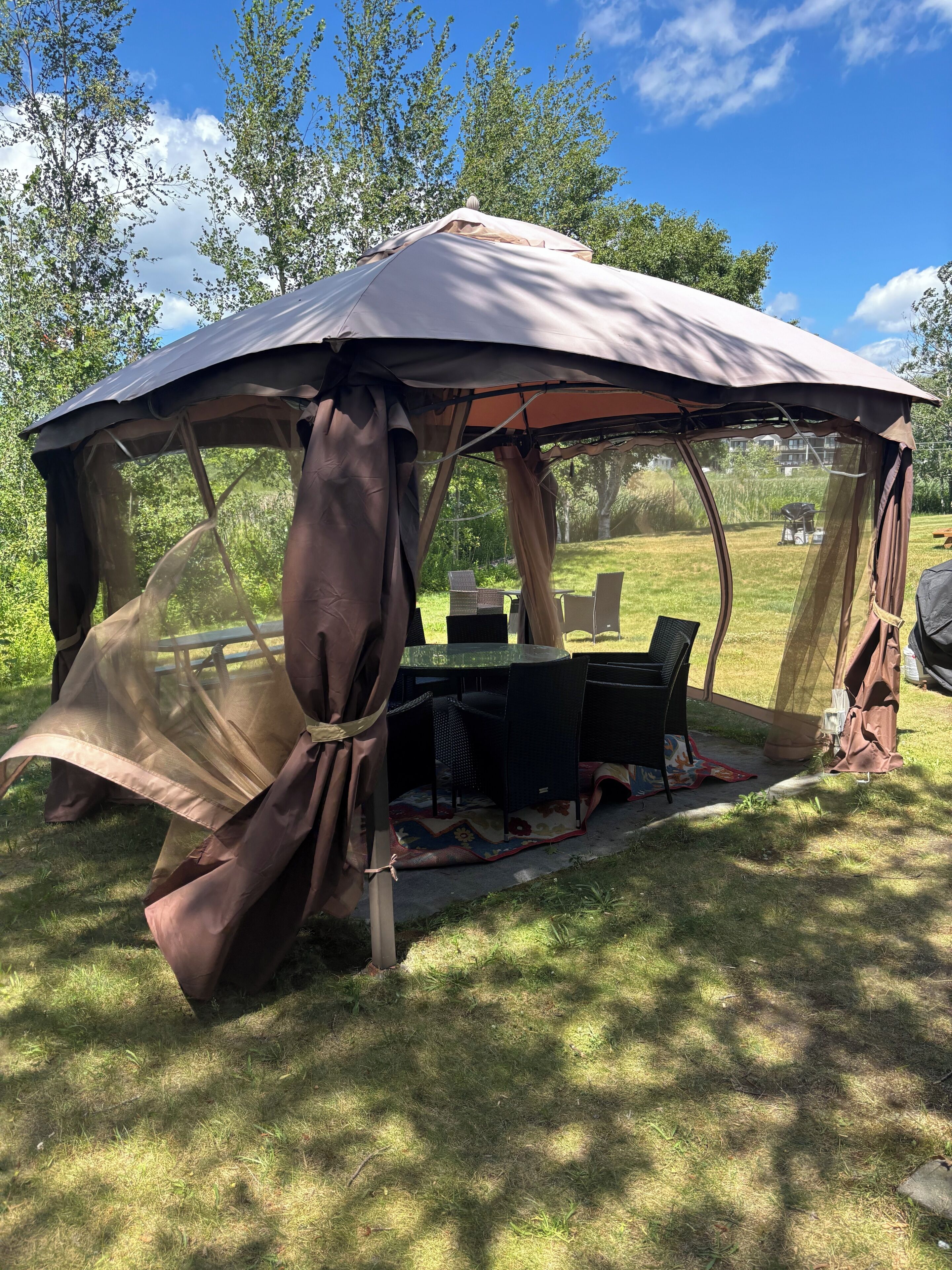 A tent with a table and chairs set up on a grassy area.