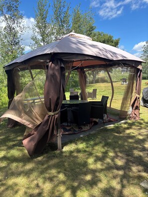 Une tente avec une table et des chaises installées sur une pelouse.