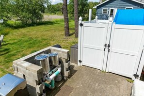 Un ensemble de cuisine portatif comprenant un gril et des récipients de rangement, une clôture blanche et une maison en arrière-plan.