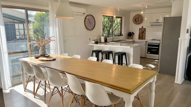 Une cuisine moderne dotée d’un îlot central, de meubles blancs et d’une grande fenêtre qui laisse entrer la lumière naturelle.