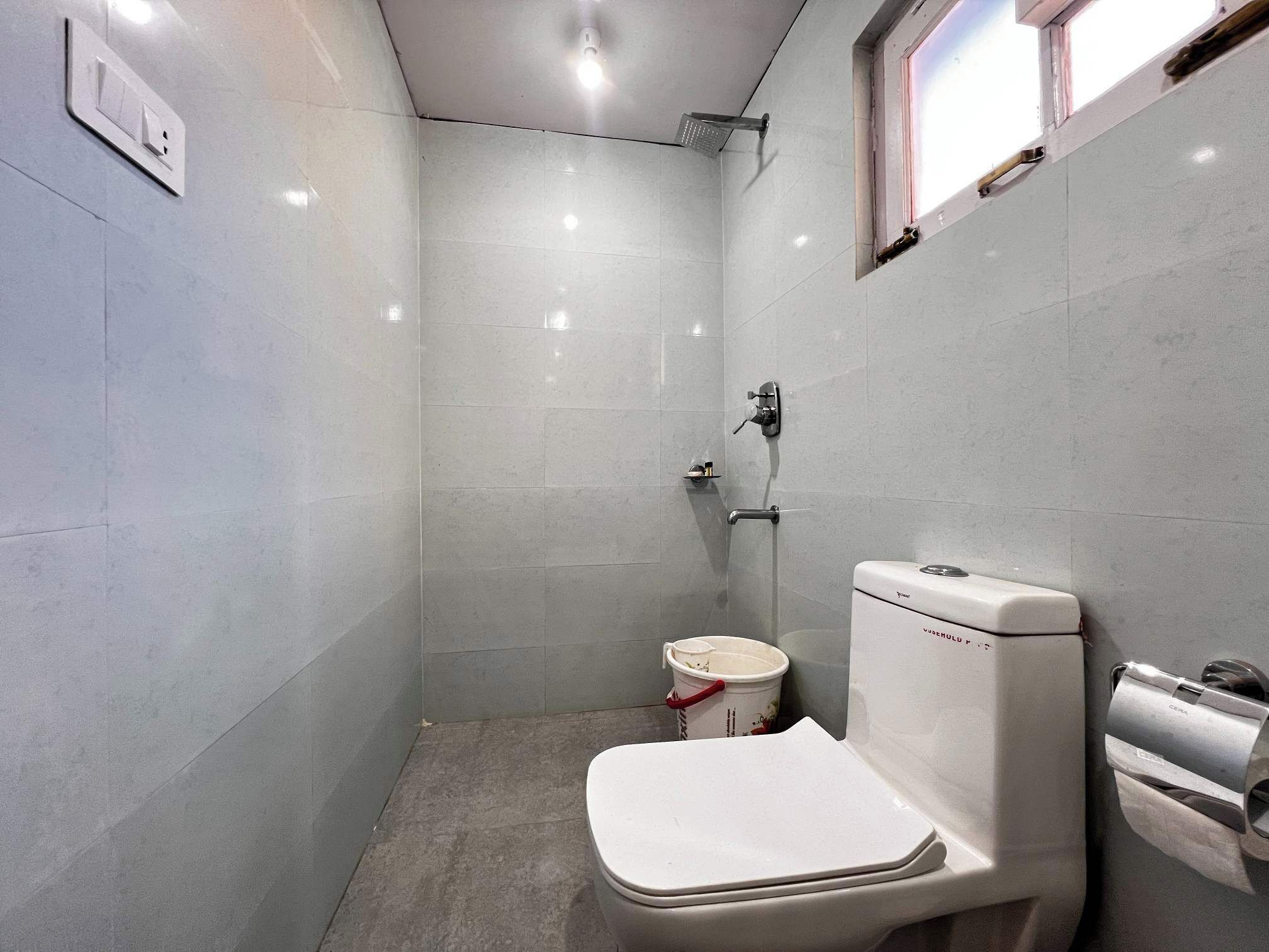 A small, compact bathroom with a toilet, a shower, and a window.
