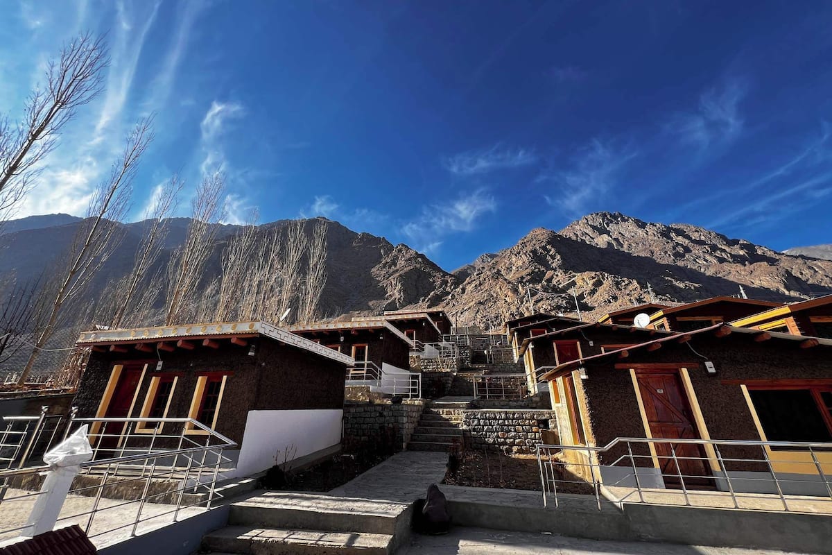 A traditional building with a staircase leading to a higher level, surrounded by mountains.