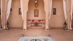 Un intérieur traditionnel avec des arches, un canapé, une fontaine et des lanternes.