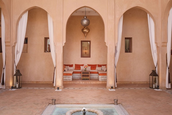 A traditional interior with arches, a sofa, a fountain, and lanterns.