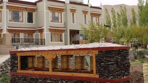 A building with traditional architecture, a stone structure with a wooden platform, and a flag on top. - House Of Stok (Leh)